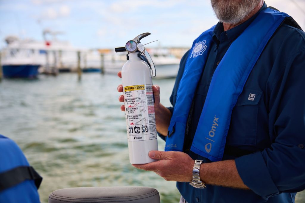 A man holds a fire extinguisher for a boat, DIY boat project concept. 