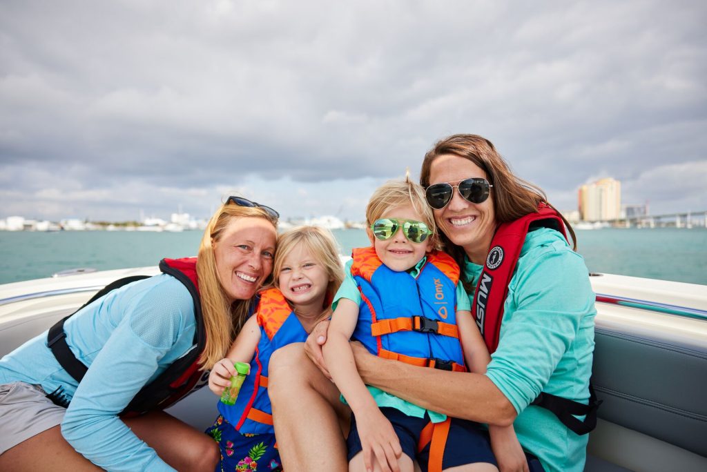 Smiling women and children wearing life jackets on a boat, buy a boat concept. 