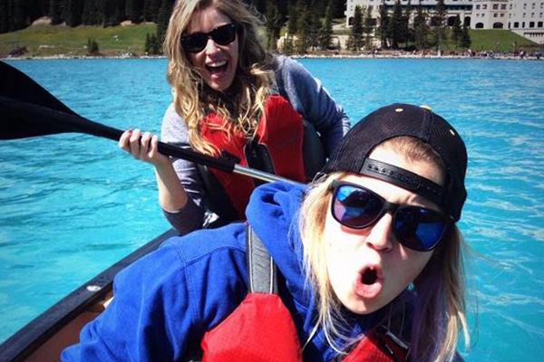 Two women having fun and wearing life jackets in a canoe.