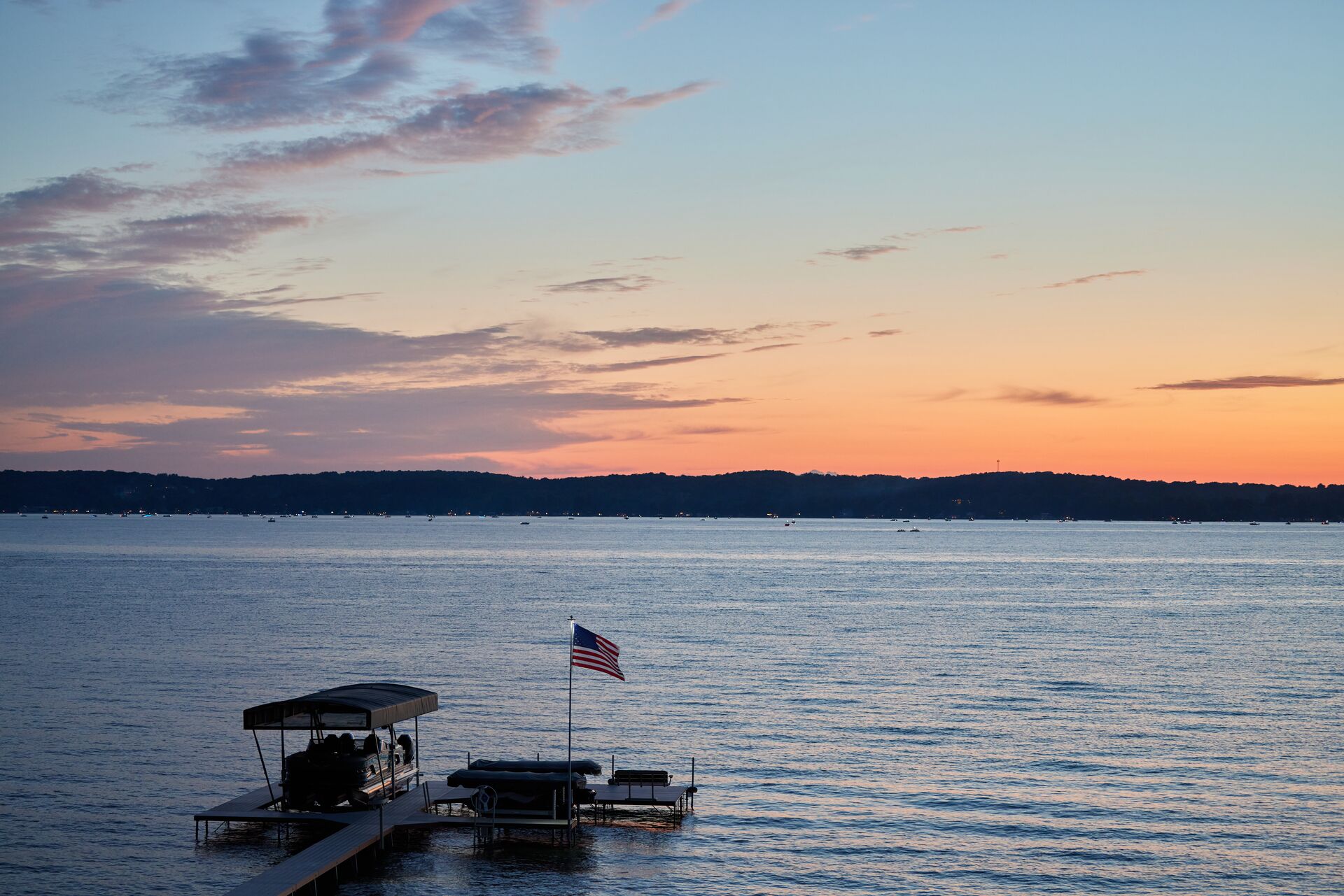 Wide view of a lake with a boat at a dock and flag, understanding Vermont boating laws concept. 