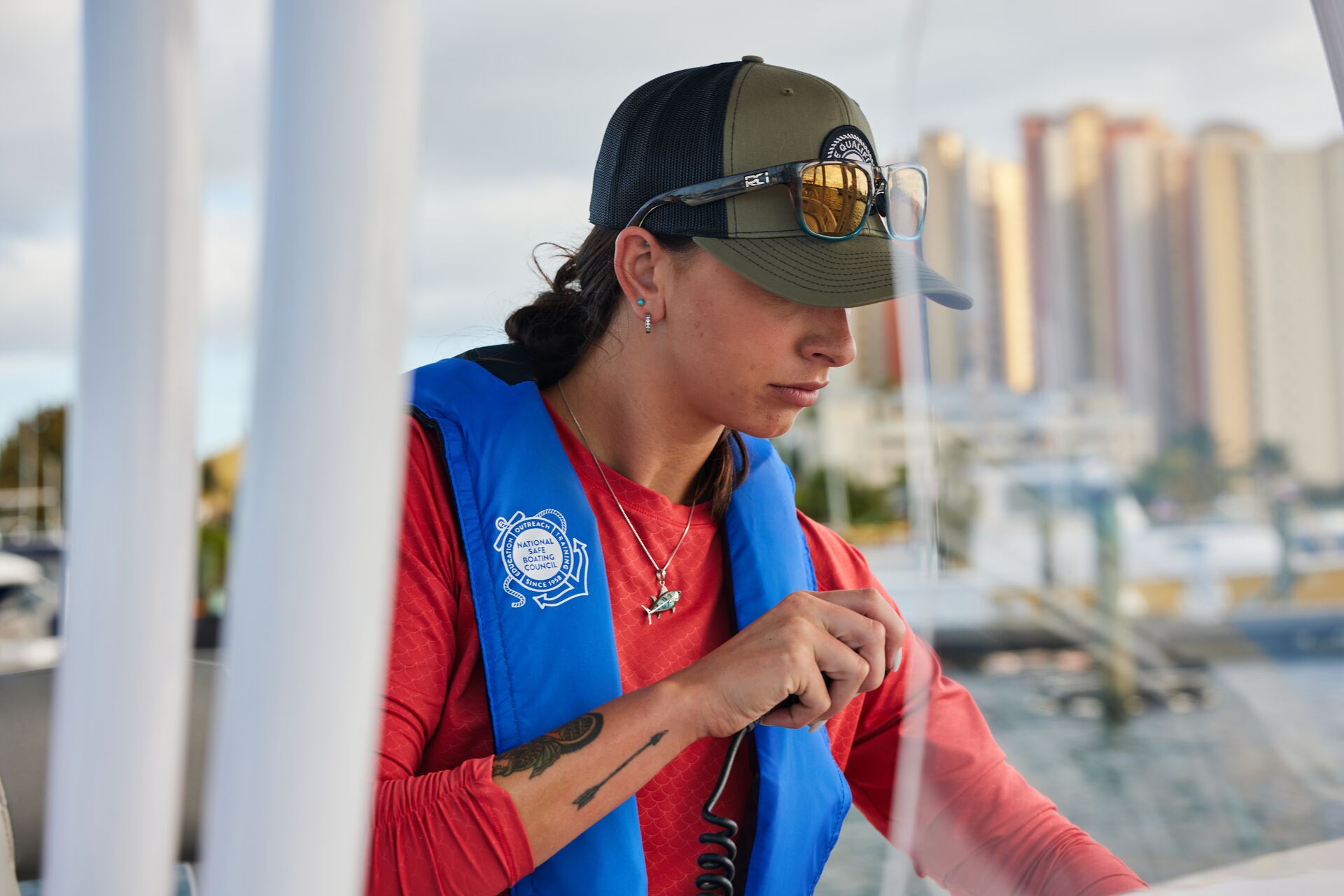 A woman in a life jacket uses a radio onboard a boat. 