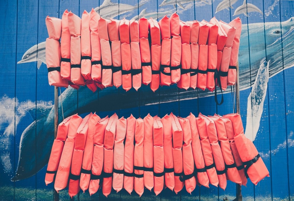 Many orange life jackets hanging on a rack, Maryland boating regulations for life jackets concept. 