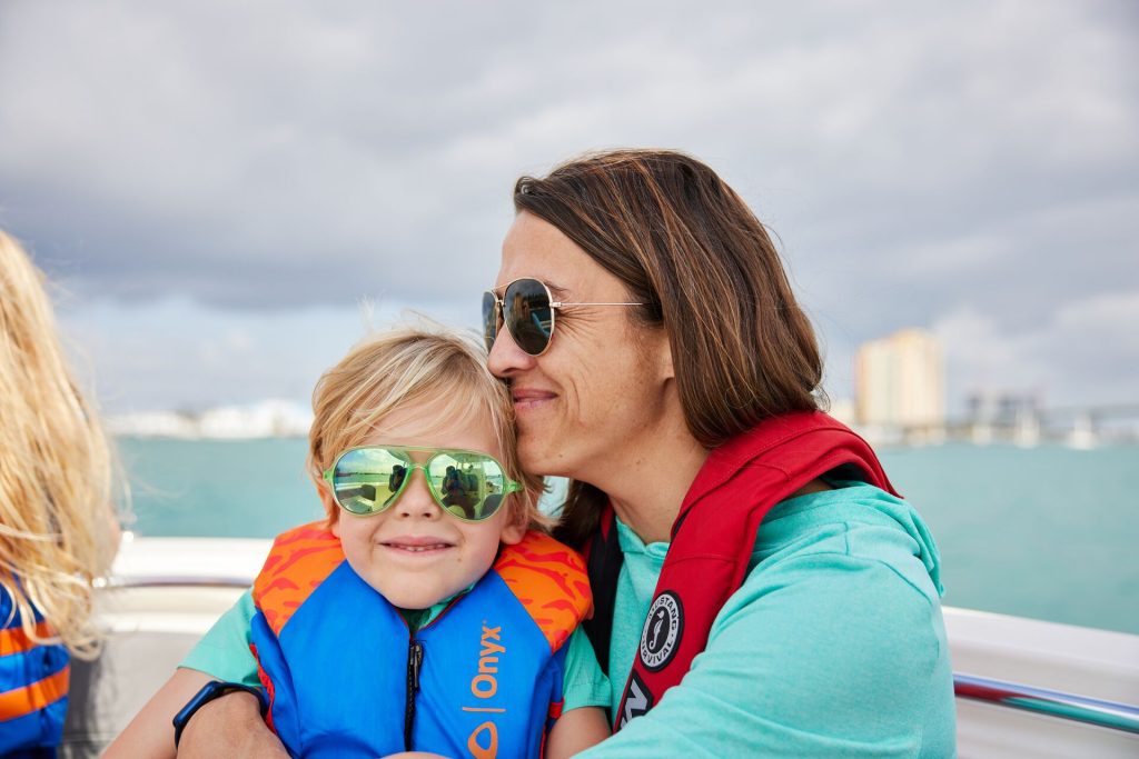 A woman hugs a child on a boat, how BOATsmart! helps people stay safe concept. 