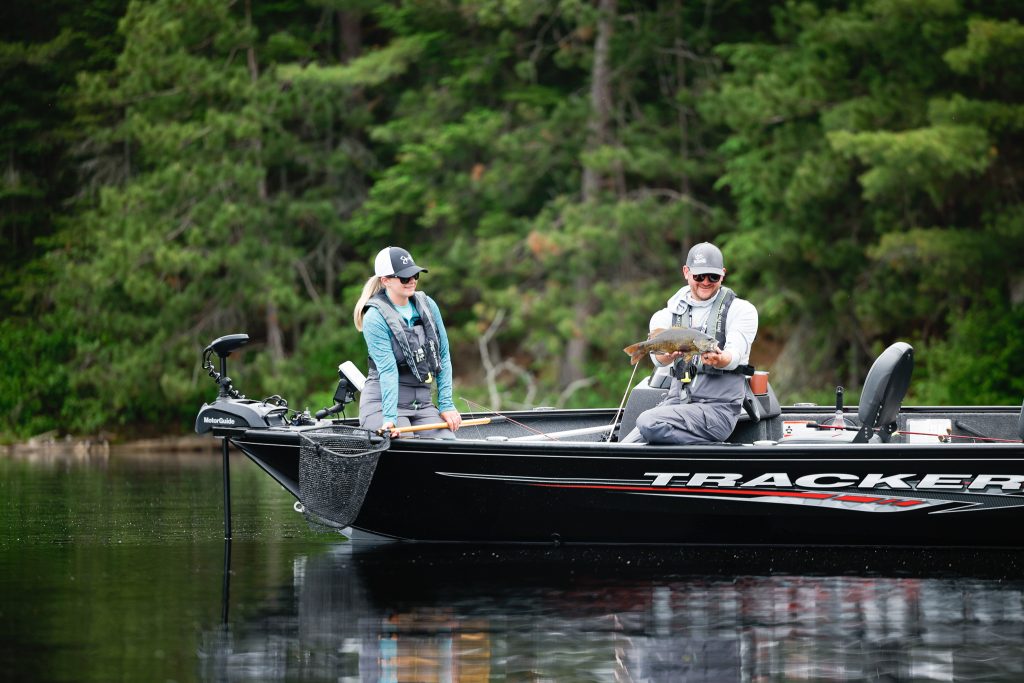 An angler holds a freshly caught fish while on a boat. 