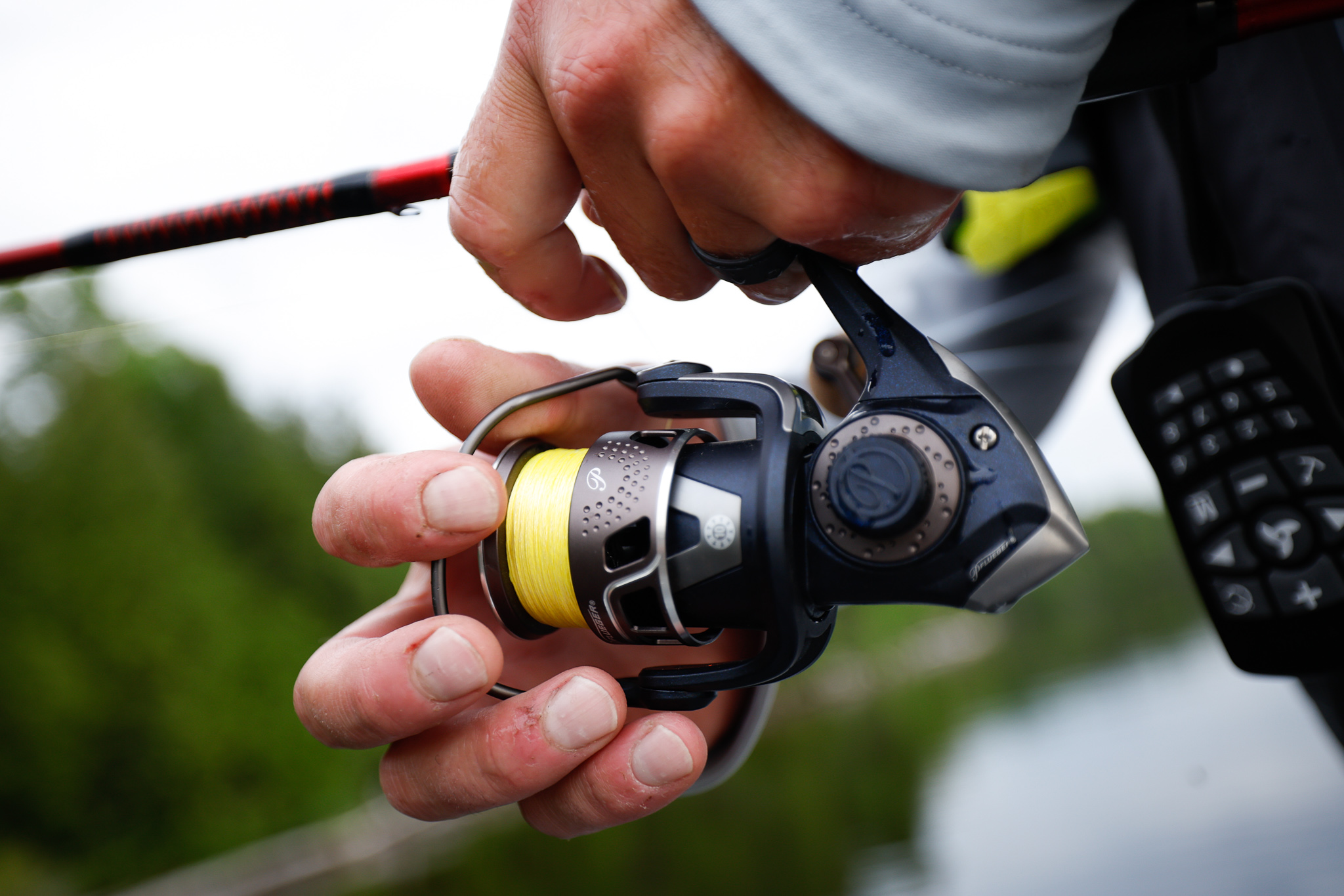 Close-up of hands holding a fishing rod and reel, using Fishbrain to find fish concept. 