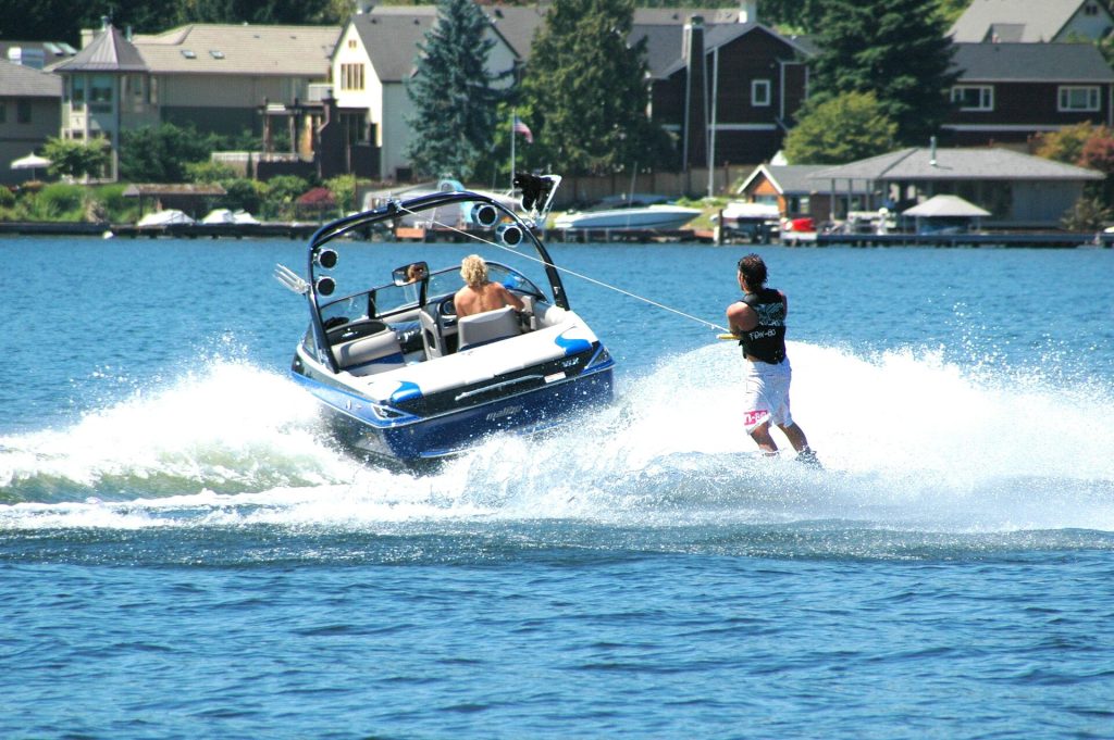 A man driving a boat while pulling a waterskier behind it. 