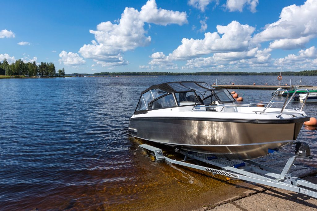 A boat on a trailer partially in the water on a boat ramp. 