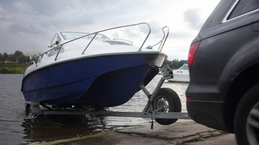 A boat on a trailer being backed into the water.