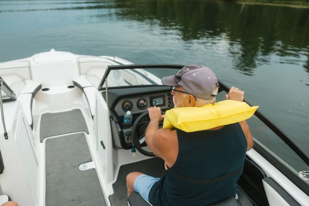 A man driving a boat while wearing a yellow lifejacket, boat registration in California concept. 