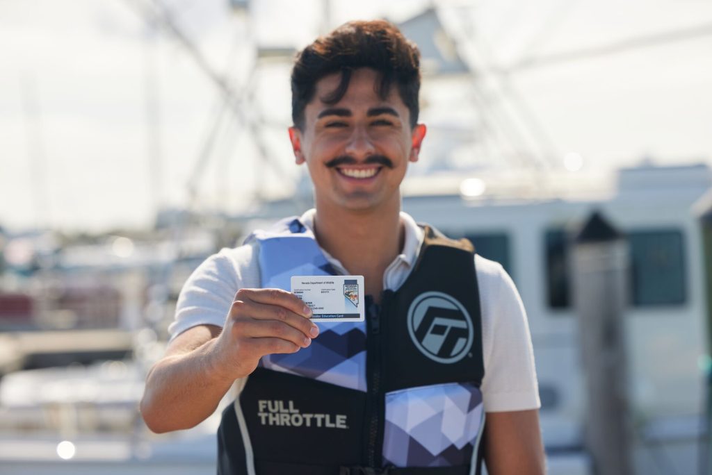 A smiling man holding a boat card wearing a life jacket, boat safely concept. 