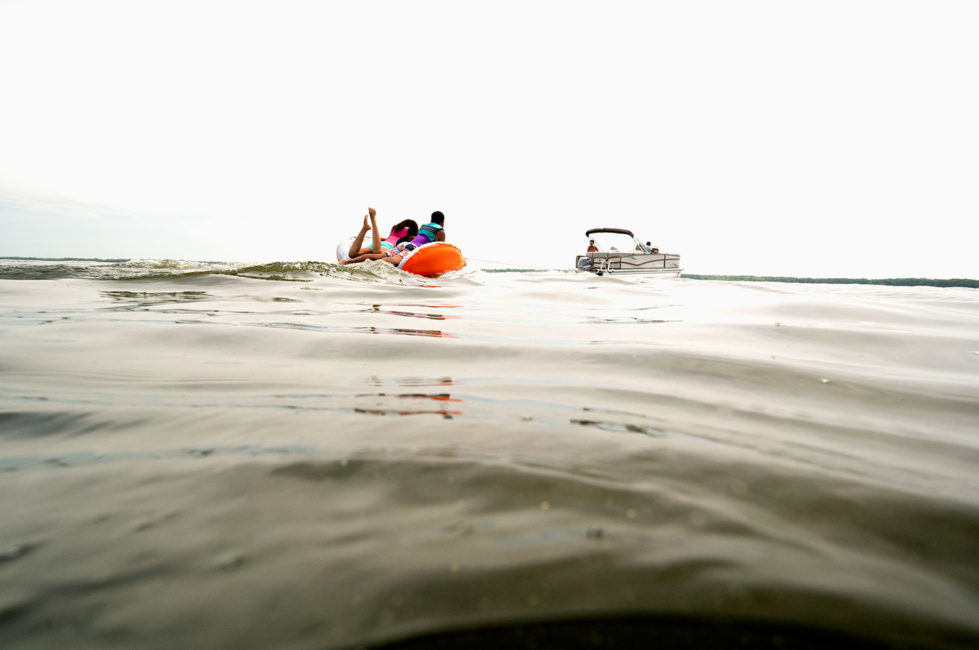 Kids on a tube behind a boat, follow Rhode Island boating laws concept. 