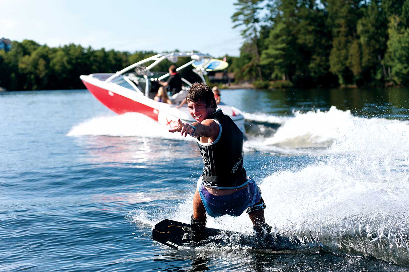 A boy riding a wake behind a boat on a lake. 