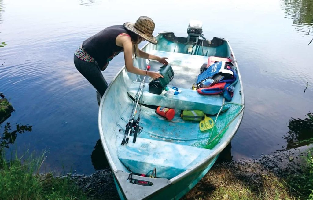 A woman putting gear in a small boat, safety geared needed for a DIY boat project concept. 