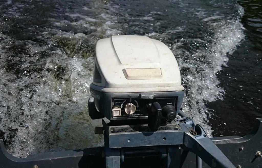 An outboard motor in the water, a DIY boat project. 