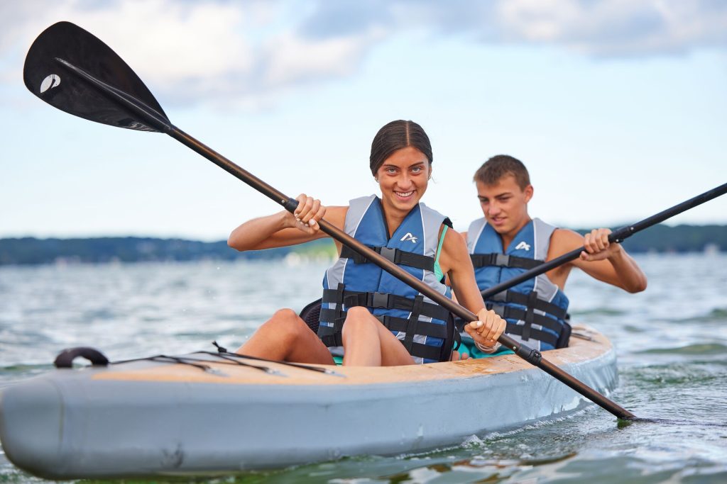 Two people paddling a canoe while wearing life jackets. 