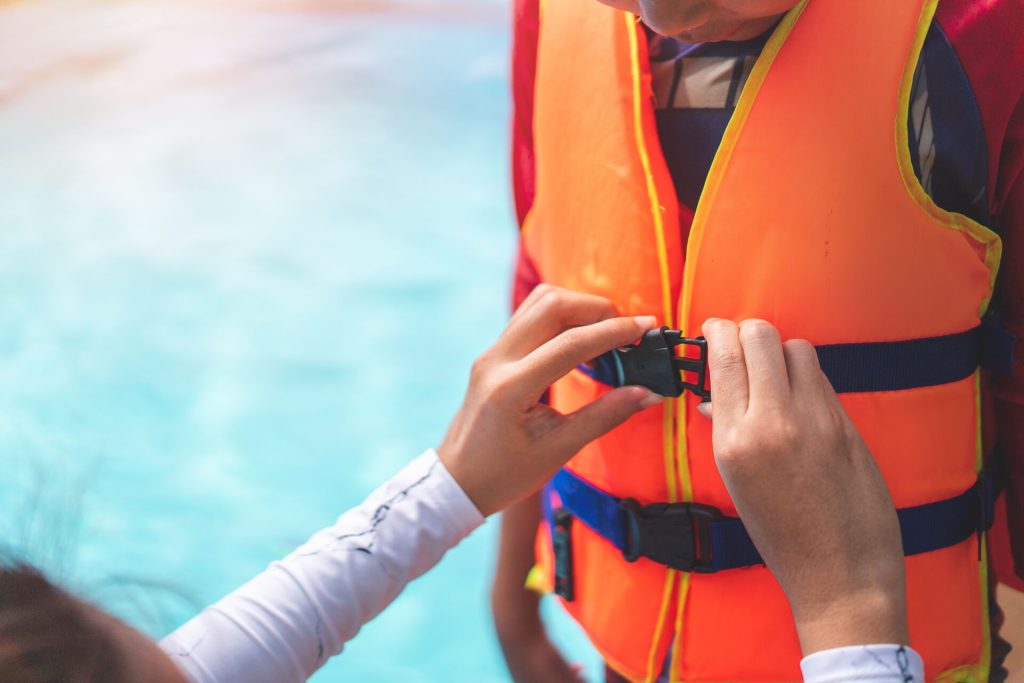 Close-up of hands fastening a life jacket for a child, follow life jacket laws in Texas concept. 