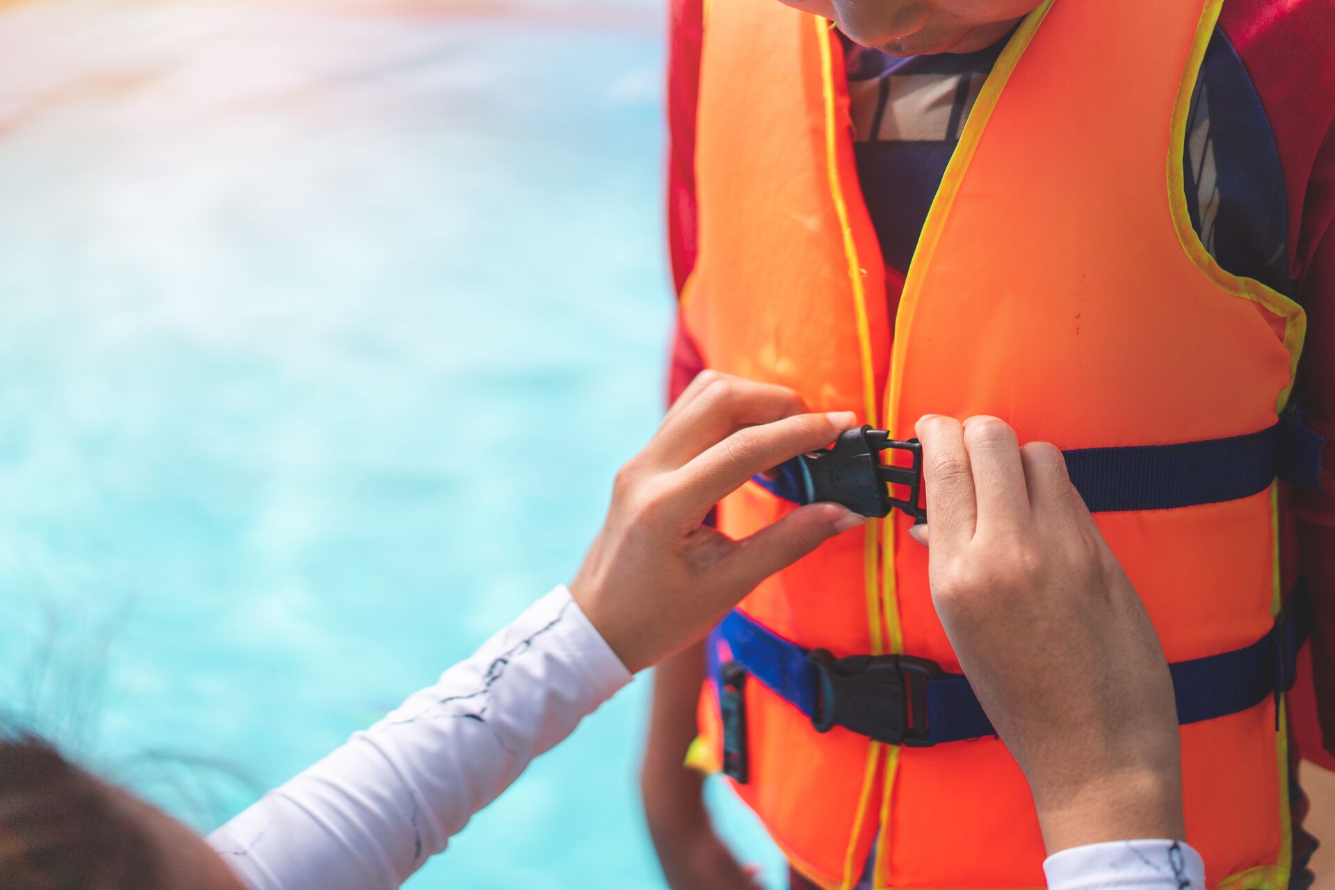 Hands fastening a life jacket worn by a child. 