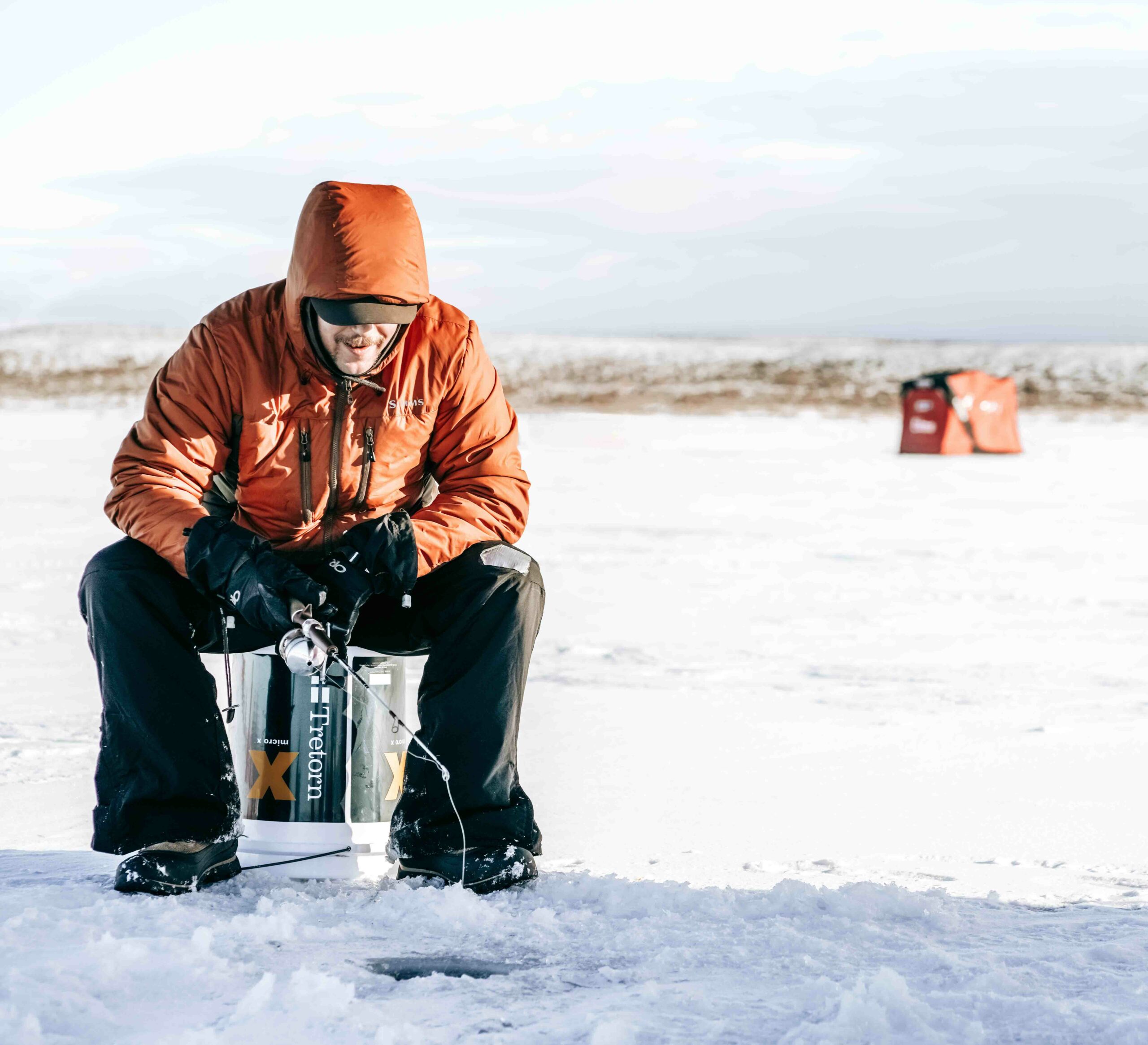 A man sitting at a fishing hole in the ice, fishing in Nunavut concept. 