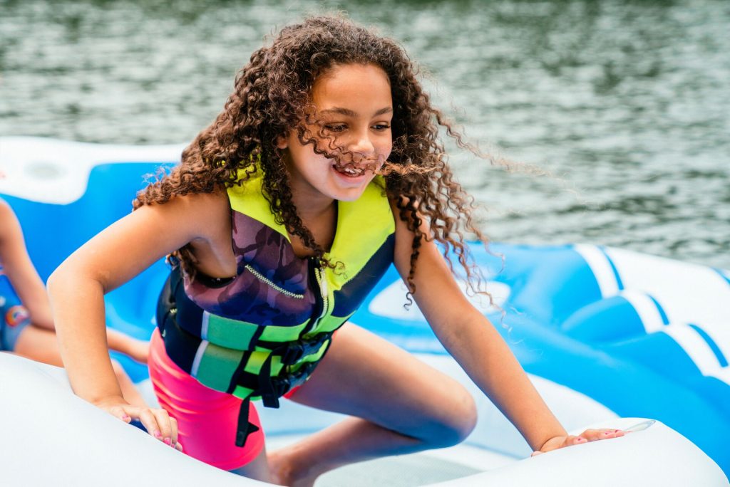 A young girl wearing a lifejacket while on an inflatable in the water. 