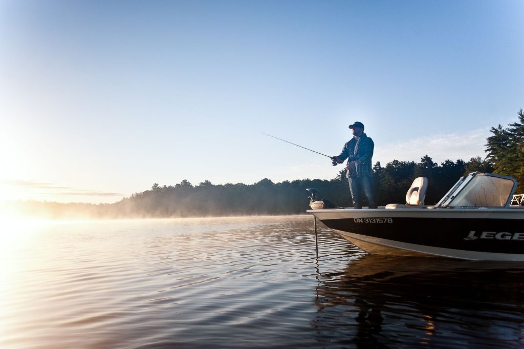 A man fishing from the front of a boat, boat registration in Manitoba concept.