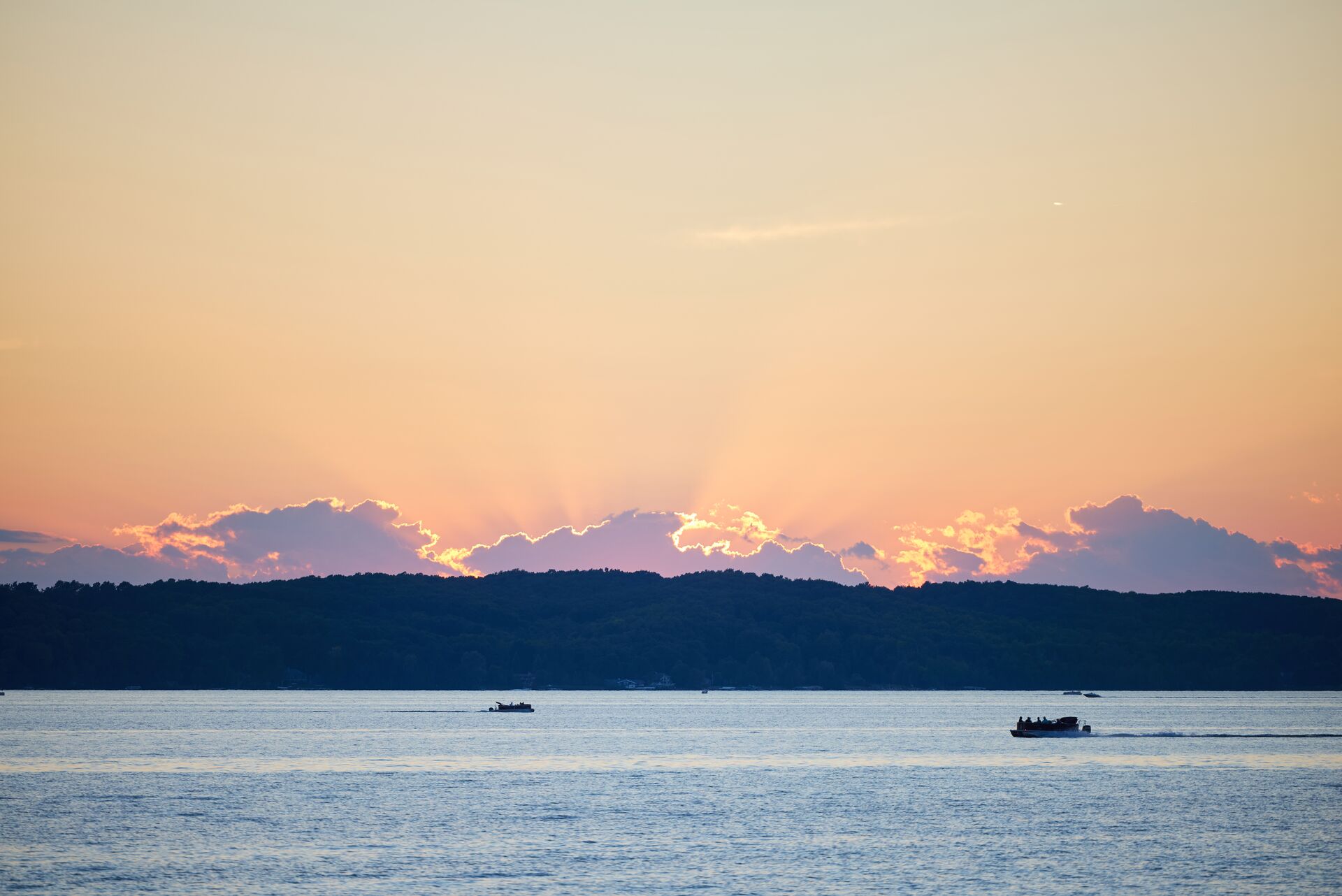 Boats in the distance on a lake with the sunset behind, boating in Nevada concept. 