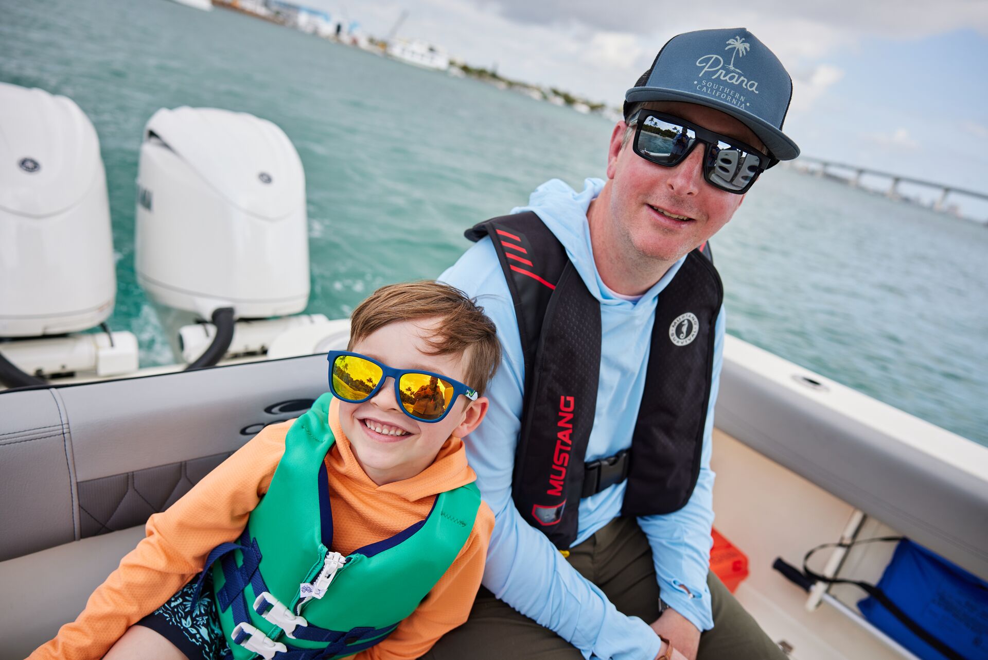 A man and boy on a boat, both wearing life jackets. 