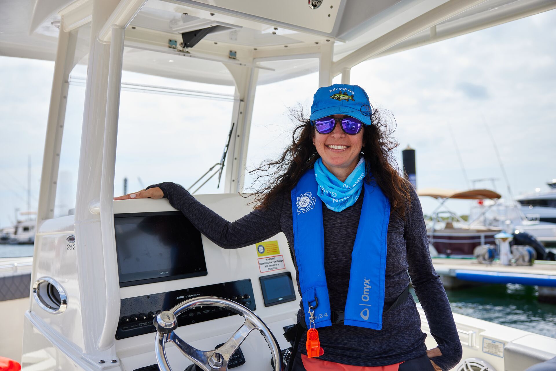 A woman smiles while wearing a life jacket on a boat, boating in Nova Scotia concept. 