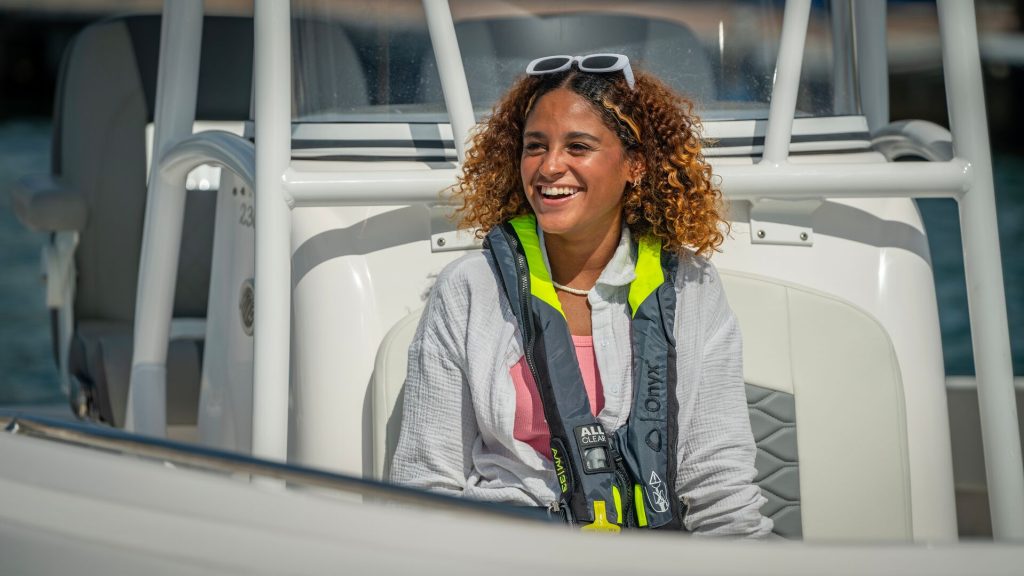 A smiling woman wearing a life jacket on a boat, can you drink on a boat in New York concept. 