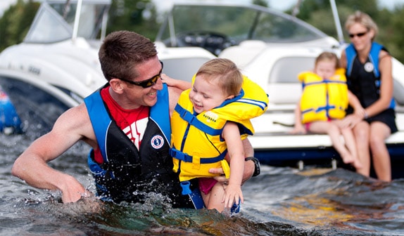 Adults and children wearing lifejackets in the water, buying children's life jackets concept.