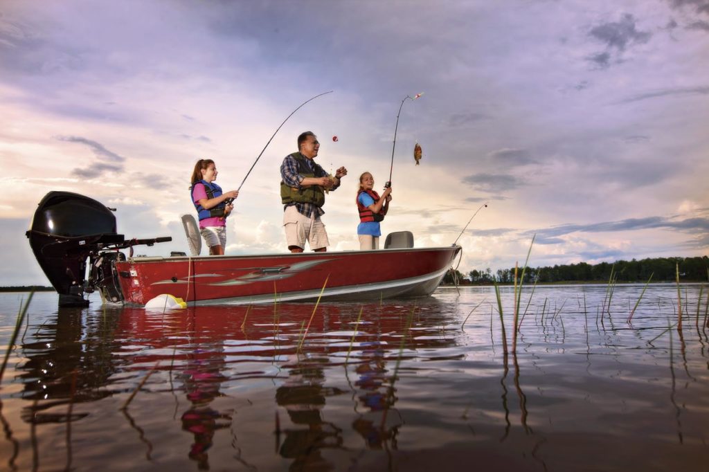 A man and two young girls fishing from a boat.