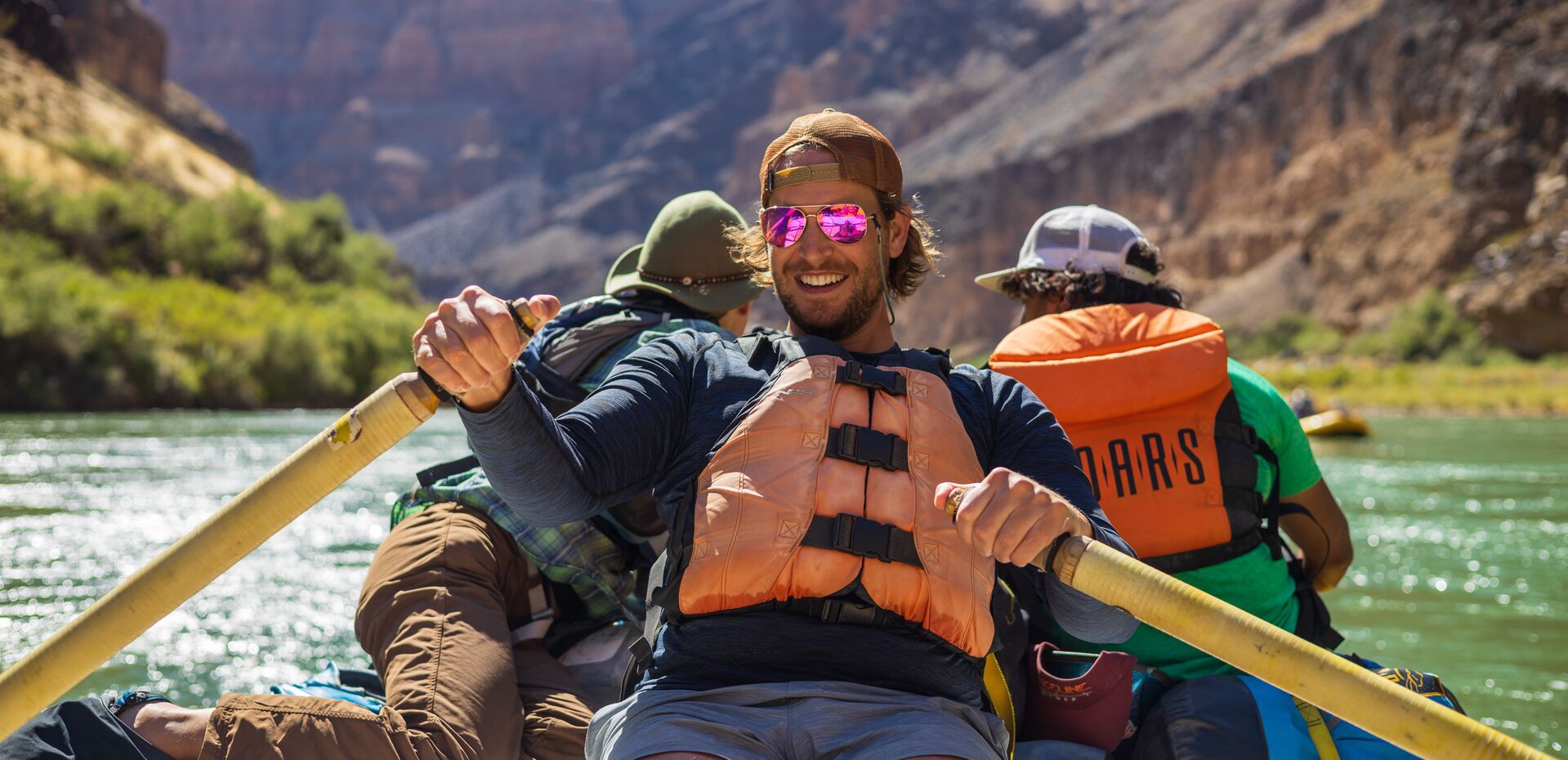 Guys whitewater rafting while wearing life jackets.