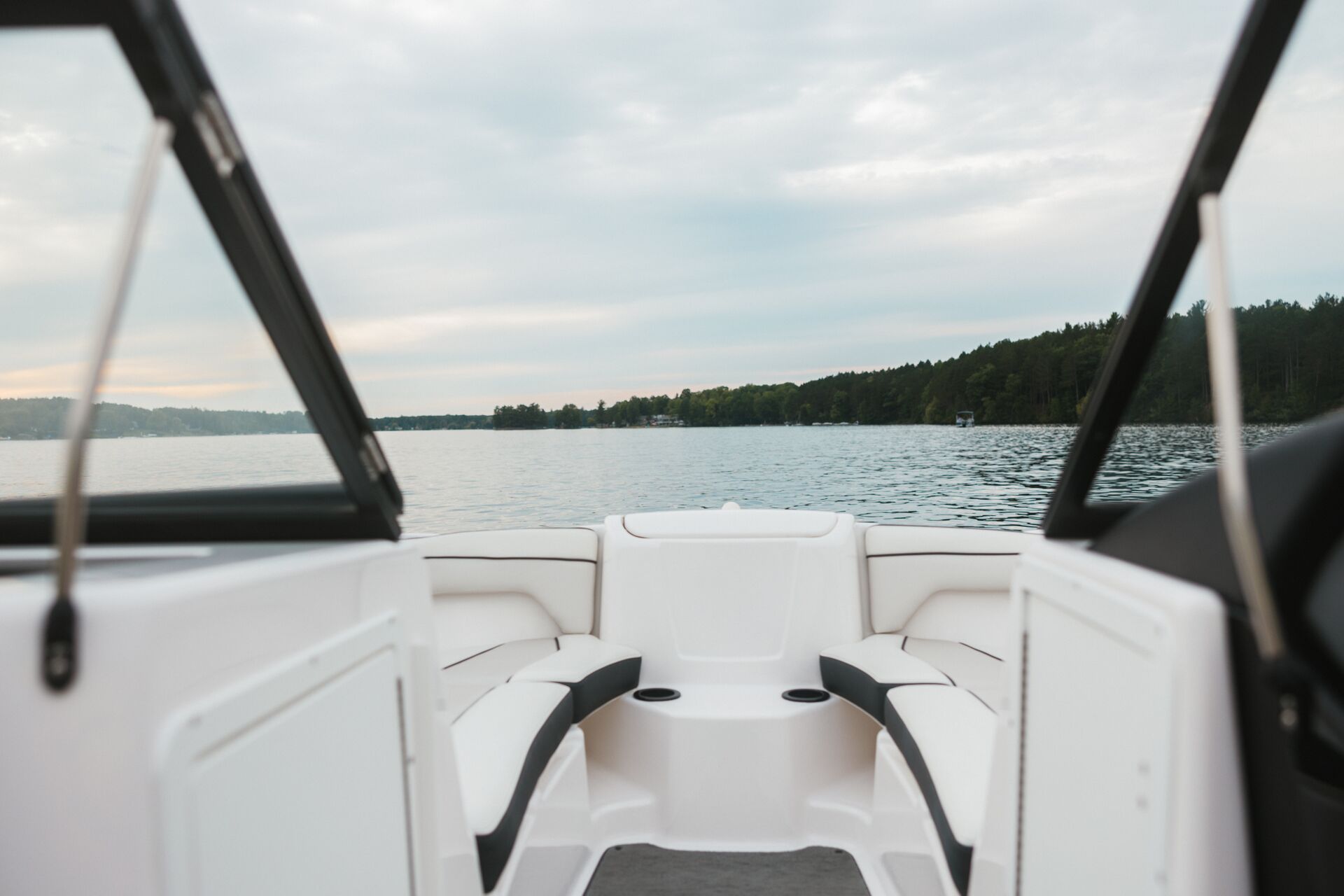 The view from the back of a boat on a lake with trees nearby, follow New Hampshire boating laws concept.