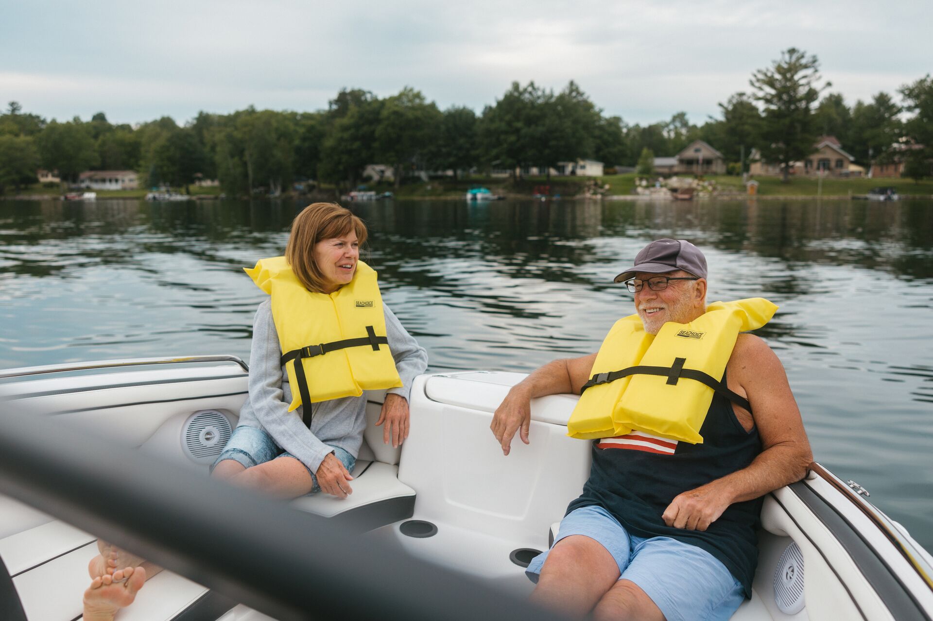 Two adults wearing life jackets on a boat on the water.