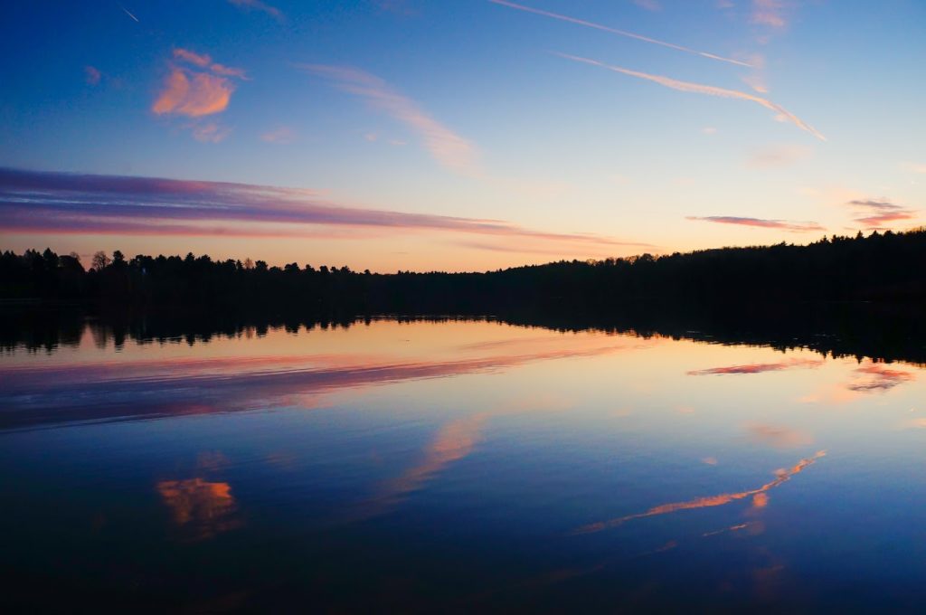 Sunset scene on a lake near trees, boating in New York concept.