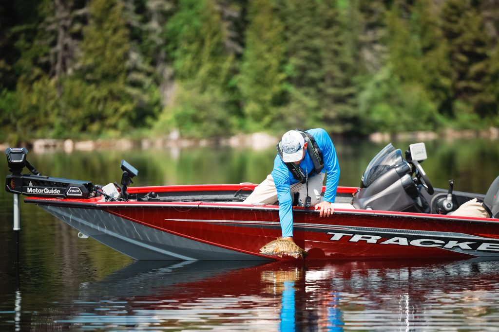 A man on a fishing boat pulls a fish out of the water, boating in Virginia concept.