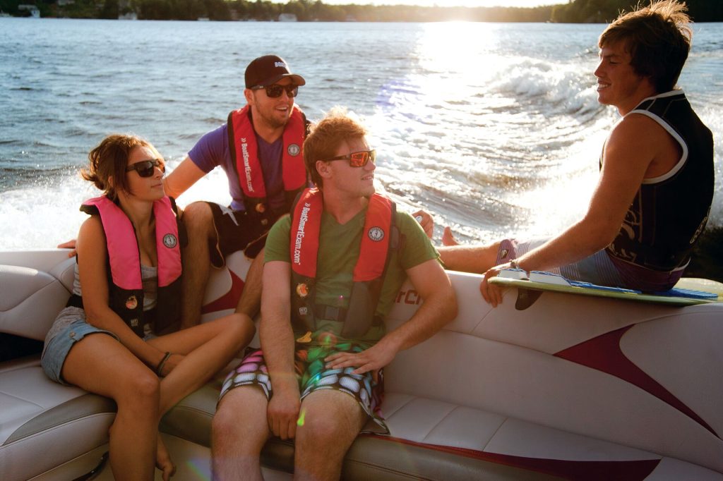 Four young people sit on a boat, avoid alcohol and boating concept.