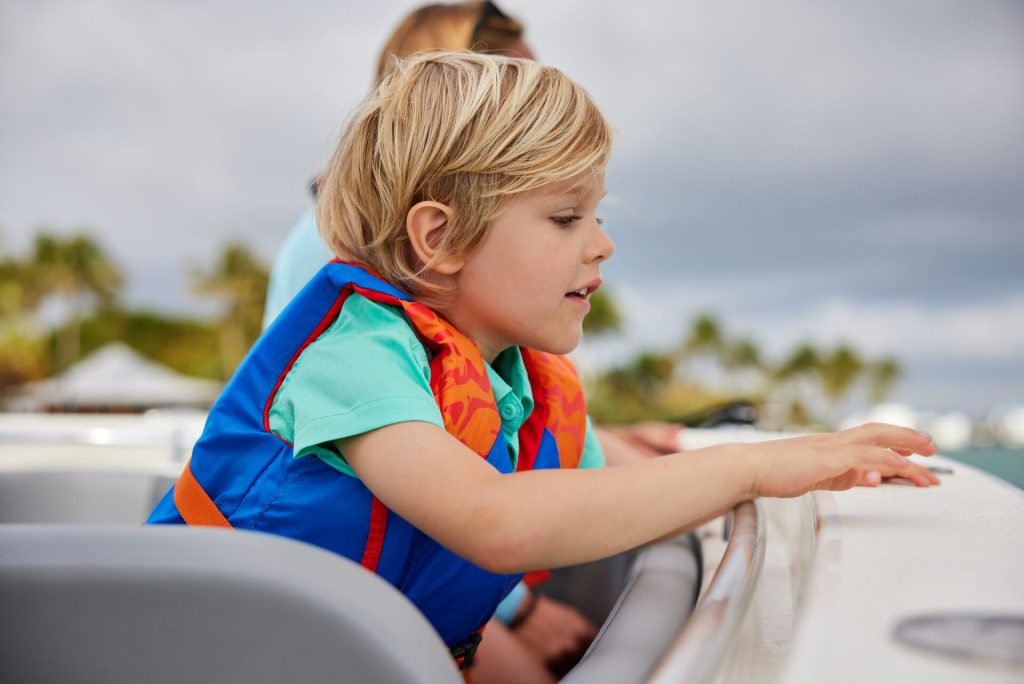 A boy in a lifejacket looks over the edge of a boat, safe boating concept.