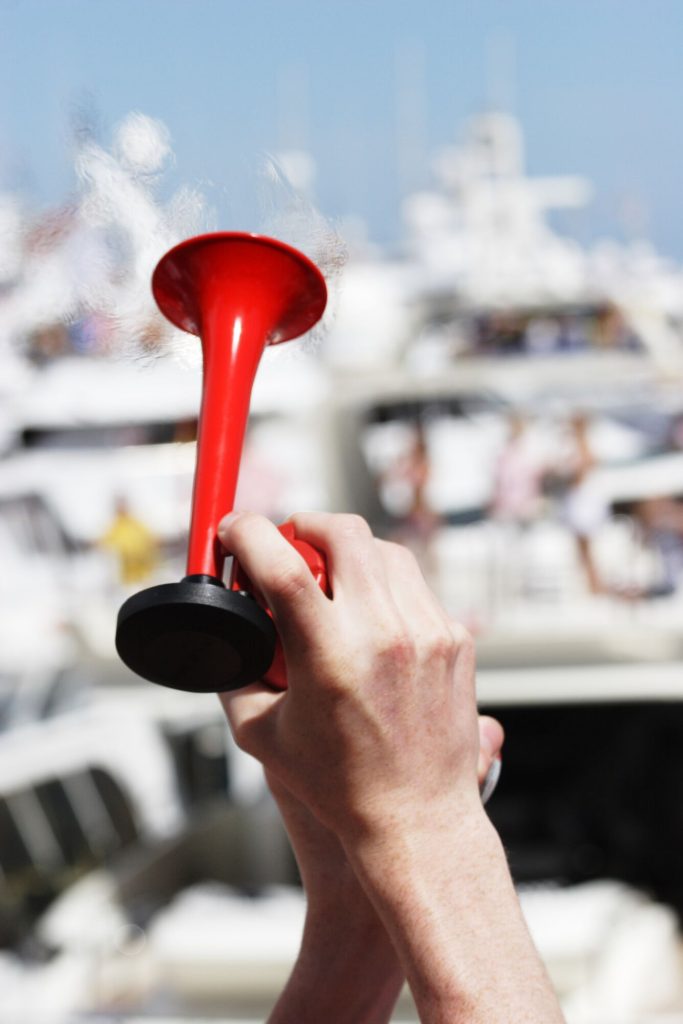 Hands holding an air horn for boat sound signals. 