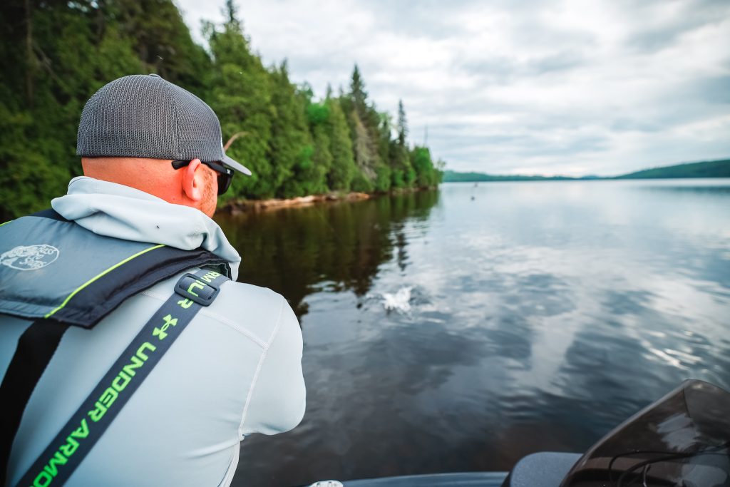 A fisherman reels in a fish while on a boat, fishing in Alberta concept. 