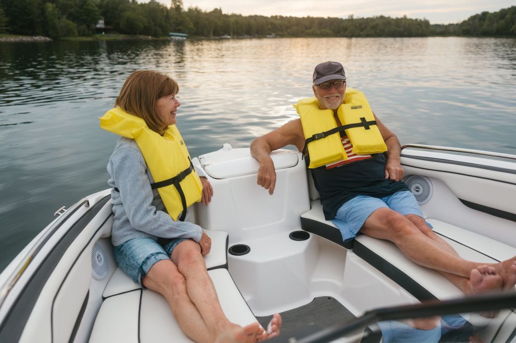 An older man and woman wearing yellow lifejackets on a boat, boating safety concept. 