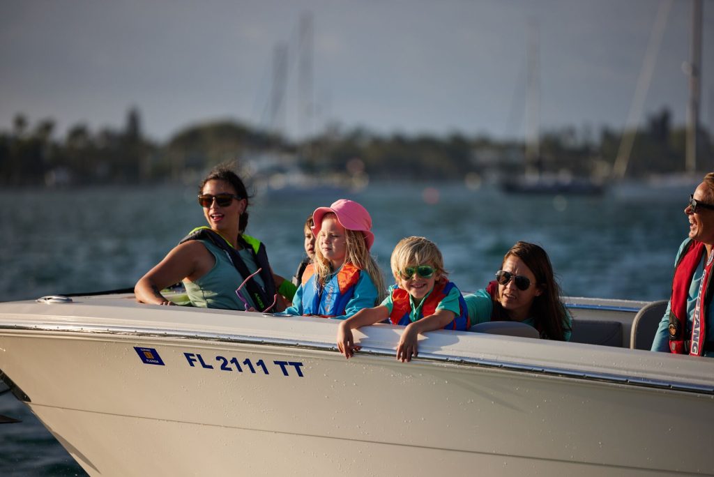 Women and kids wearing lifejackets at the front of a boat, safe boating concept. 